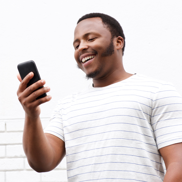 cool smiling young black man looking at mobile phone